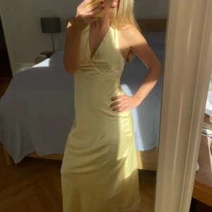 Ljusgul långklänning med knyt - Långklänning i ljusgul nyans från peppermayo med v-ringad front och knyt i ryggen. Klänningen är ärmlös och har en slät, elegant form som framhäver siluetten. Perfekt för sommarens alla tillfällen. Materialet känns mjukt och lätt. Köpte för 1200kr säljer för 800kr