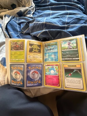 Pokémonkort i samlarpärm - Säljer en samling Pokémonkort i en pärm med plastfickor. Blandade kort med olika Pokémon, tränare och energikort. Perfekt för dig som vill utöka din samling eller börja samla. Flera klassiska och moderna kort ingår.