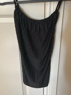 Svart plisserad topp  - Snygg plisserad svart topp från Gina Tricot med smala axelband som går i kors baktill. Lätt i tyget och därför väldigt skön att bära under varma dagar. Fungerar även som en fest topp🤩
