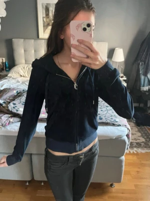 Mörkblå velour hoodie Juicy Couture - Mörkblå hoodie i mjuk velour från Juicy Couture med dragkedja framtill, broderad logga på bröstet och justerbar huva. Perfekt för en avslappnad och trendig look. Denna är knappt andvänd därav priset💞