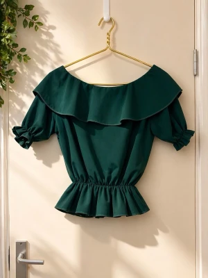 Grön blus med volang och puffärm - Säljer en mörkgrön blus med bred volang runt halsen och puffiga korta ärmar. Blusen har elastisk midja och är tillverkad i ett mjukt syntetmaterial. Perfekt för dig som gillar en feminin och trendig look.