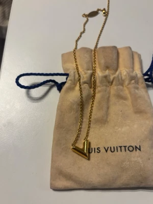  Louis Vuitton Essential V Halsband - Snyggt halsband från Louis Vuitton med ett V-format hänge i guldton. Kommer med original påse från Louis Vuitton. Materialet är metall med guldfinish. Fick det i present 2022 av en närstående, köptes på Louis Vuitton i Paris 🥰 Säljer det då det inte kommer till användning som förr!