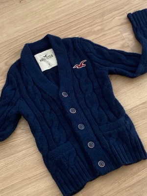 Hollister cardigan - Säljer en riktigt fet Hollister Cardigan. Denna är välkänd och många söker den. Skicket är 10/10. Storleken är S. Priset kommer ligga på 599kr men kan sänkas.