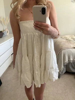 Vit axelbandslös kortklänning - Söt vit axelbandslös kortklänning med smock upptill och volangig kjol. Perfekt till studenten eller sommaren 