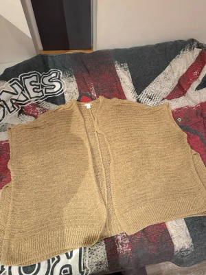 Beige stickad väst från H&M - Säljer en beige stickad väst från H&M i storlek XS/S. Västen är öppen framtill, har en avslappnad passform och är gjord i ett luftigt, grovstickat material. Perfekt att slänga över en t-shirt eller långärmad för en chill look.