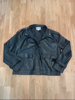Svart skinnjacka från NA-KD - Super snygg och stilren skinnjacka från NAKD. Jättefint skick, storlek 34 men sitter lite lite oversized som den gör på dockan på bild 2🫶passar perfekt som jacka till vår och sommar