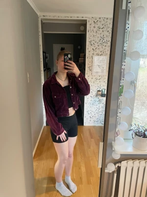 Vinröd croppad velvet jacka - Säljer en vinröd croppad velvet jacka med klassisk krage och silver knappar framtill. Jackan har långa ärmar och en avslappnad passform och är i velvet tyg.