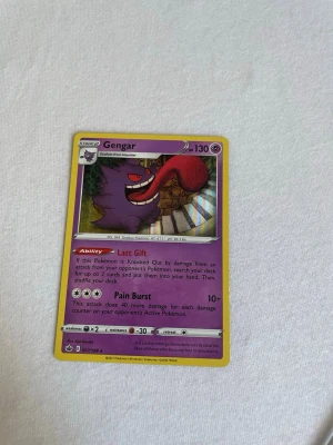 Pokémonkort Gengar - Säljer ett Pokémonkort med Gengar, lila och gul ram, från Sun & Moon-serien. Kortet har coolt motiv med Gengar och detaljerad text om attacker och förmågor. Perfekt för samlare eller Pokémonfans som vill utöka sin kortlek.