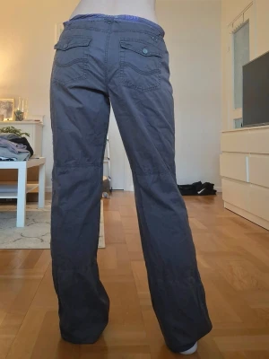 Low waisted cargobyxor med fickor - Äkta vintage cargo-byxor med stämpel “1989” på en knapp bak ✨ Storlek 28 och passar som S–M. Mid waist, men kan även stylas som low waist genom att vika ner kanten eller bära dem lite lägre. När kanten viks ner syns ett lila tyg på insidan som ger en cool touch✨️  Midjemått: 40 cm Innerbenslängd: 85 cm 