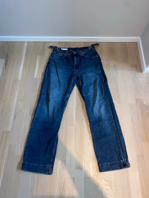 Mörkblå raka jeans från Zara - Säljer ett par mörkblå jeans med rak passform. Jeansen har klassiska fem fickor, bälteshällor och stängs med dragkedja och knapp. Tillverkade i slitstark denim som ger en tidlös look.