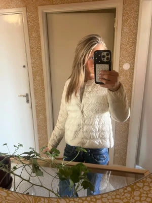 Vit dunjacka från Uniqlo Ultra Light - Säljer en vit dunjacka från Uniqlo Ultra Light Down. Jackan är lätt, har dragkedja framtill och en enkel, stilren design. Perfekt för kalla vinterdagar och enkel att matcha med olika outfits. Tillverkad i slitstarkt material med vattenavvisande yta.