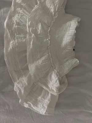 Vit volangkjol med spetsdetaljer - Söt vit kjol med bred smock i midjan, volanger och fina spetsdetaljer. Kjolen har en romantisk känsla med flera lager och mjukt, lätt tyg som ger ett flowy fall. Storlek xxs men passar mig som vanligt viss har xs-s och är 170 lång 