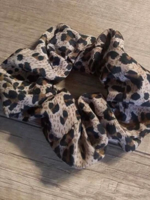 Leopardmönstrad scrunchie - Säljer en scrunchie med leopardmönster i beige, brunt och svart. Hårsnodden är gjord i ett mjukt tyg som ger en snygg och trendig look till din frisyr. Perfekt accessoar för dig som vill addera lite edge till din stil.