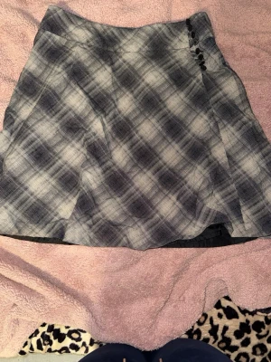 Kjol med knappar - Kjolen har knappar på sidan som man kan knäppa upp vid på och avtag. Den har dubbelt tyg. Ett litet hål långt ner som knappt syns. Den är knälång