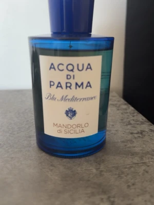 Acqua di Parma  - Fräsch parfym från Acqua di Parma, Mandorlo di Sicilia, i serien Blu Mediterraneo. Flaskan är djupblå och cylinderformad med vit etikett och blå text. Eau de toilette med italiensk känsla och exklusiv design, perfekt för dig som gillar eleganta dofter. 150 ml. Går även att byta ut mot andra parfymer