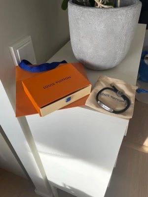 Louis Vuitton armband -  Säljer ett LV-armband i fint skick. Svart band med silverdetalj, stilrent och passar både till vardag och lite mer uppklätt.  Använt få gånger och fortfarande i väldigt bra skick. Kommer med original box, dustbag och allt annat OG.  Priset kan diskuteras! 