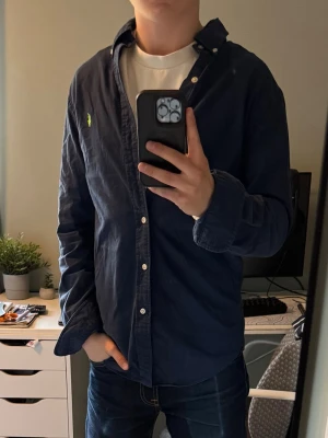 Mörkblå Polo Ralph Lauren skjorta  - Säljer en mörkblå/navy/marinblå skjorta från Ralph Lauren med neongrön brodyr. Den är i storlek small slim fit. Självklart äkta. Den har inga defekter och är i mycket bra skick. Alla lappar är kvar.