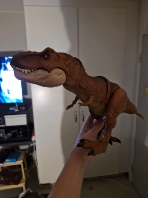 Brun T-Rex dinosaurie leksak - Säljer en cool T-Rex dinosaurie leksak i brun plast med svarta detaljer och vita tänder. Perfekt för dig som gillar dinosaurier eller vill ha något unikt till samlingen. Leksaken har realistisk form och detaljerade klor. Något du kan ge till dina barn om dem gillat dinosaurier 