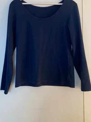 Mörkblå långärmad topp från Avet - En enkel och stilren mörkblå långärmad topp från Avet. Toppen har rund halsringning och är tillverkad i ett mjukt, stretchigt material som känns bekvämt mot huden. Perfekt att matcha med jeans eller kjol för en clean look.