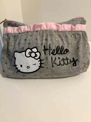 Hello Kitty necessär grå med prickar - Söt necessär från Hello Kitty i grått tyg .Dragkedja upptill och mjukt material. Perfekt för smink eller småprylar.