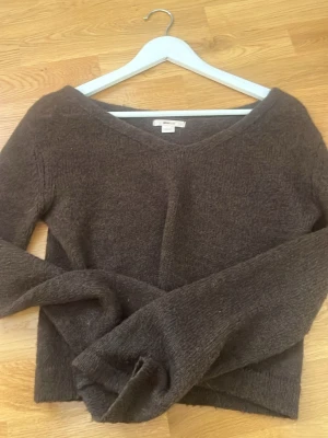 Brun stickad tröja från Gina Tricot - Mysig brun stickad tröja från Gina Tricot med v-ringning och långa ärmar. Tröjan har en enkel och avslappnad passform, perfekt för lager på lager. Materialet är mjukt och ger en skön känsla. Passar dig som gillar basic men ändå vill ha något stilrent.