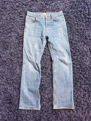 Filippa K jeans - Snygga ljusblå jeans från Filippa K med rak passform och klassisk femficksdesign. Jeansen har en enkel knappstängning och är gjorda i ett mjukt denimtyg som känns bekvämt hela dagen. Perfekta för en avslappnad och stilren look. Hör av er vid minsta fundering!