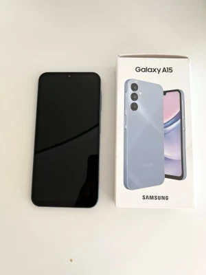 Samsung Galaxy A15 blå Android-mobil - Samsung Galaxy A15 i snygg blå färg med stilren design och rundade hörn. Telefonen har tre kameror på baksidan och en stor skärm på framsidan. Tillverkad i glas och plast, levereras med originalkartong. Perfekt för dig som vill ha en modern Android-telefon.