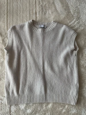 Ärmlös stickad väst Tiger of Sweden - Säljer en ärmlös stickad väst från Tiger of Sweden. Västen har ribbade kanter vid halsringning, ärmhål och nederkant. Perfekt att styla över en skjorta eller t-shirt för en trendig lager-på-lager-look.