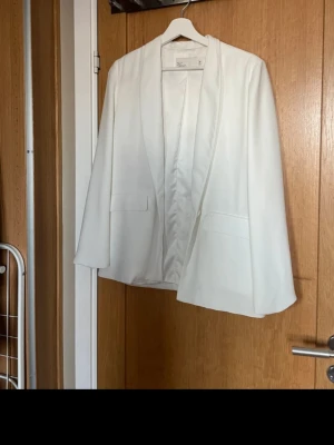 Vit kavaj från NLY Trend, storlek 36 - Stilren vit kavaj från NLY Trend i storlek 36. Kavajen har en rak passform, två fickor framtill.