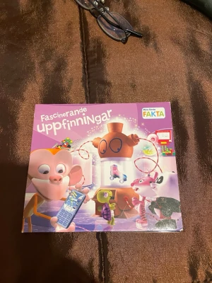 Fascinerande uppfinningar cd - En färgglad barnbok med titeln 'Fascinerande uppfinningar' från serien Mina första Fakta. Omslaget är lila och pryds av tecknade djurfigurer och olika uppfinningar. Boken är illustrerad och riktar sig till yngre läsare som vill lära sig om spännande uppfinningar.