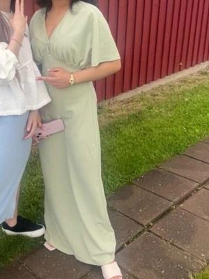 Ljusgrön långklänning med v-ringning - Snygg ljusgrön långklänning med v-ringad hals och korta ärmar. Klänningen har en avslappnad passform och är perfekt för varma dagar. Enkel och stilren design som passar till många tillfällen. Pris kan alltid diskuteras❤️