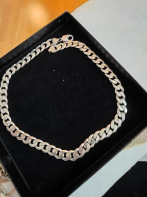 Silver halsband  - Säljer ett stilrent halsband i silverfärg med breda, platta länkar i klassisk kedjedesign. Perfekt accessoar för att lyfta din outfit med en modern touch. Levereras i svart ask.