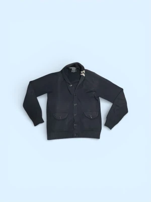  Woolrich cardigan  - Stilren svart kofta från Woolrich med knäppning framtill, två fickor med lock och ribbade muddar. Snygg detalj med två beige ränder på kragen. Perfekt för lager på lager och passar till det mesta.