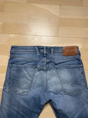 Blå Replay Anbass jeans - Säljer ett par blå jeans från Replay med snyggt tvättad finish och klassiska fem fickor. Nypris ligger på över 1600kr men vi säljer dessa för endast 599kr! Hör gärna av er vid frågor eller funderingar!