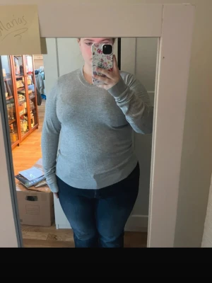 Grå basic långärmad tröja - Enkel och stilren grå långärmad tröja med rund halsringning. Tröjan har en rak passform och är tillverkad i ett mjukt och stretchigt material, perfekt för en avslappnad look. Inga synliga loggor eller detaljer.