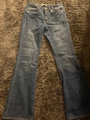 Blå bootcut jeans från Levi's - Säljer ett par klassiska blå bootcut jeans från. Jeansen har den ikoniska röda Levi's-lappen bak och är gjorda i mjuk denim. Perfekta för en avslappnad och trendig look.