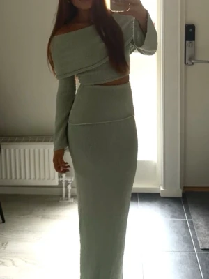 Ljusgrön offshoulder croppad topp - Trendig ljusgrön offshoulder topp med lång ärm och croppad passform. Toppen har en snygg omlott-design och är tillverkad i ett mjukt, stretchigt material som ger en bekväm känsla. Perfekt att matcha med höga kjolar eller byxor.