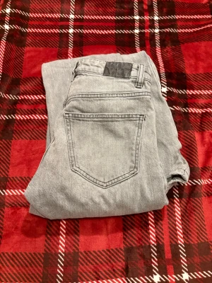 Grå jeans från Gina Tricot - Snygga grå jeans från Gina tricot i klassisk femficksmodell. Jeansen har raka ben och är tillverkade i ett mjukt denimtyg som ger en avslappnad look. Perfekta för dig som gillar stilrena och enkla plagg.