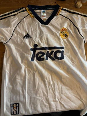 Retro Real Madrid Ronaldo matchtröja 2002 - Jag säljer en retro Real Madrid tröja från 2002 med den legendariska Ronaldo Nazario på ryggen. Perfekt för dig som älskar fotboll och retrostil.