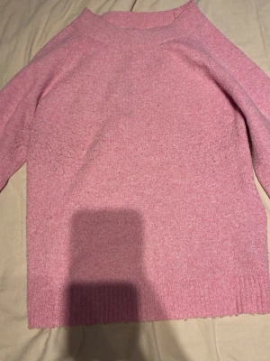 Rosa stickad tröja från Vero Moda - Mysig rosa stickad tröja från Vero Moda med rund halsringning och ribbade muddar. Tröjan har en enkel och stilren design, perfekt att matcha med jeans eller kjol. Materialet är mjukt och bekvämt för kalla dagar. Lite nopprig men annars jätte bra