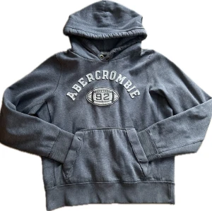 Vintage Abercombie & Fitch hoodie(extremt sällsynt)  - Snygg grå vintage hoodie från abercombie. Hoodien är extremt sällsynt och fanns bara ett limiterat antal när den såldes runt 90-talet, Därför priset! Hoodien har en Klassisk känguruficka och ribbade muddar vid ärmar och nederkant. Mjuk bomullskänsla och avslappnad passform, perfekt för chill dagar.