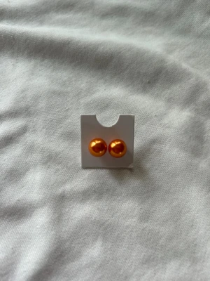 Orange pärlörhängen - Snygga örhängen med klara orange pärlor i rund form. Perfekta för dig som vill ha en färgklick till din stil. Klassisk design med stift och metallbaksida. Passar till många olika looks och är lätta att bära hela dagen.