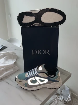 Dior B30 - ljusblå/vit/grå med reflexer - Säljer ett par riktigt feta och somriga B30s i storlek 42. Perfekt färger nu inför sommaren och passar både med jeans och shorts. Pris kan alltid diskuteras vid snabb affär! Fraktar inom 0-1 dagar alltid👋