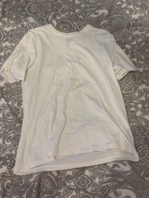 Vit basic t-shirt i bomull - En klassisk vit t-shirt i mjuk bomull med rund hals och korta ärmar. Perfekt att matcha med jeans eller shorts för en enkel och stilren look.
