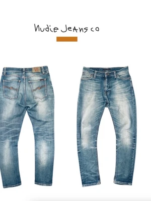 Blå slitna jeans från Nudie Jeans - Säljer ett par ljusblå jeans från Nudie Jeans med slitna detaljer och snygg tvätt. Klassisk femficksmodell med orange sömmar och Nudie-logga på bakfickan. Jeansen har rak passform och är tillverkade i bomull. Hör av dig vid minsta fundering