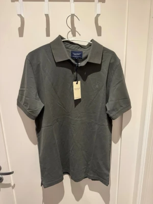 Pikétröja - Snygg grå pikétröja från Douglas Hayward med klassisk krage och korta ärmar. Tillverkad i double mercerised bomull för extra mjuk och lyxig känsla. Perfekt till jeans eller chinos för en clean look. Helt ny, aldrig använd. Nypris 140€ vilket blir 1500kr.