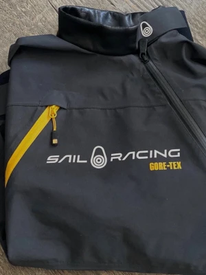 Sail Racing Orca Spraytop Gore tex vindjacka  - Sail Racing Orca spray top i gortex. Jackan är av äldre modell vilket innebär att neonepron tyget ( det vid nacken/kragen) har åldrats och ser lite slitet. Jackan är i utmärkt skick för övrigt och har inga defekter. Så till dig som söker en cool vindjacka så passa på och gör ett klipp. En ny Orca jacka ligger på rek pris 3000kr 