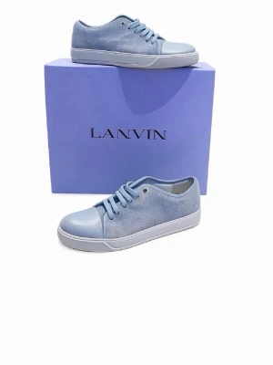 Blå sneakers från Lanvin - Snygga ljusblå sneakers från Lanvin med klassisk låg profil. Skorna har snörning, tåparti i skinn och sidor i mocka för en stilren och modern look. Perfekta för dig som vill ha något unikt och trendigt i garderoben.