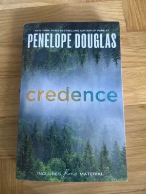 Credence av Penelope Douglas - Säljer boken 'Credence' av Penelope Douglas. Omslaget har en mystisk skog i gröna och blå toner med titeln i färgglada bokstäver. Boken är på engelska och innehåller bonusmaterial. Perfekt för dig som gillar romantisk och spännande skönlitteratur.