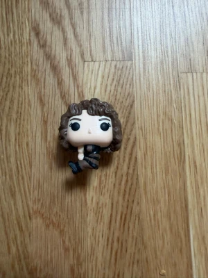 Funko Pop, Nancy from stranger things - Säljer en Funko Pop samlarfigur med brunt lockigt hår och stora svarta ögon. Figuren har svarta kläder och svarta skor, och är tillverkad i plast. Perfekt för dig som gillar popkultur och vill ha en cool dekoration till rummet.